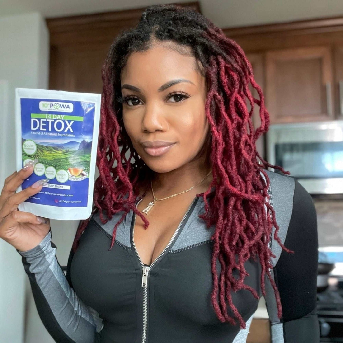 Woman holding colon parasite cleanse kit detox tea package in kitchen setting